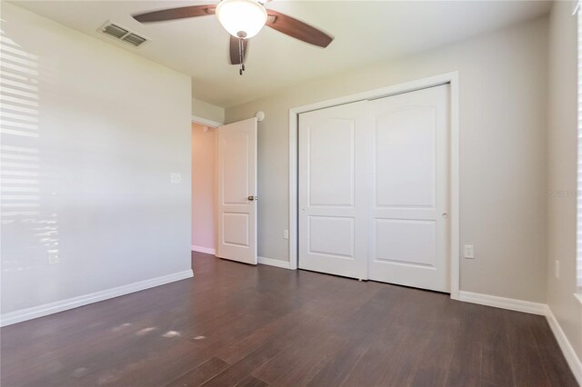 unfurnished bedroom with ceiling fan, dark wood-type flooring, visible vents, baseboards, and a closet