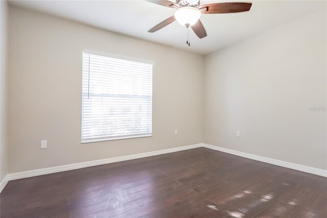 empty room with dark wood-style floors, ceiling fan, and baseboards