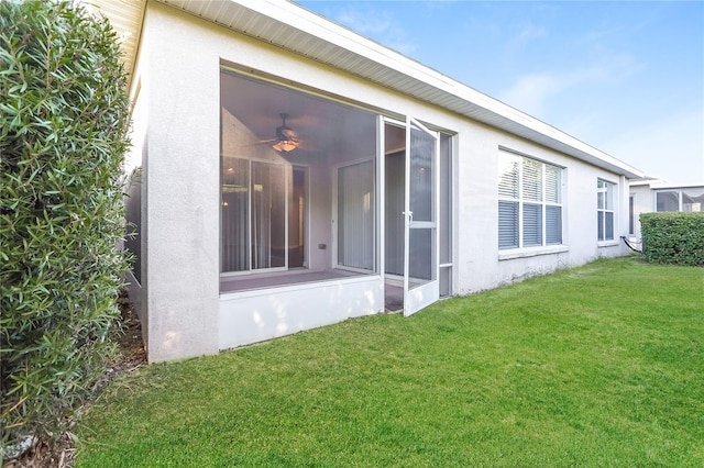 view of property exterior featuring a sunroom, a yard, and stucco siding