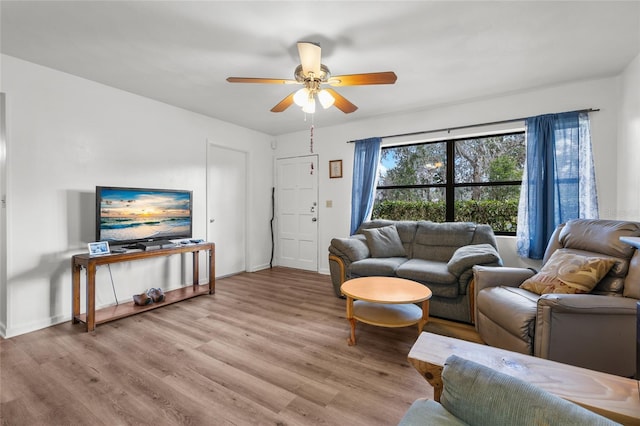 living room featuring baseboards, a ceiling fan, and light wood-style floors