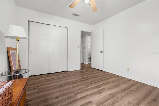 unfurnished bedroom with baseboards, a closet, visible vents, and wood finished floors