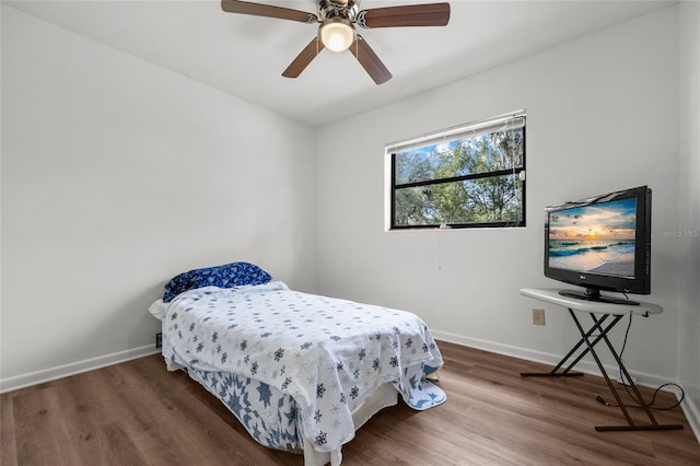 bedroom featuring ceiling fan, baseboards, and wood finished floors