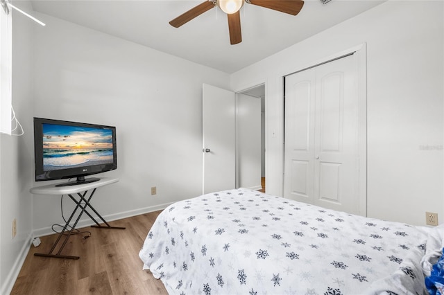 bedroom featuring ceiling fan, a closet, baseboards, and wood finished floors