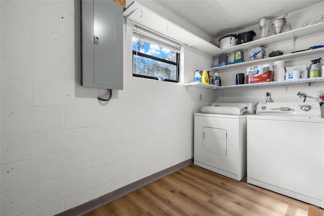 laundry room with laundry area, light wood-style floors, electric panel, washer and clothes dryer, and concrete block wall