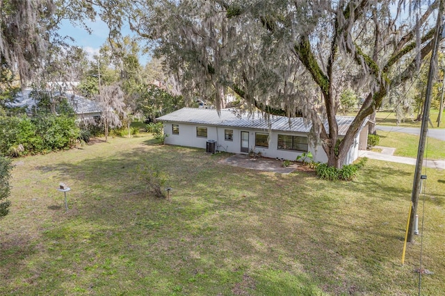 view of front of house featuring central AC, metal roof, and a front lawn