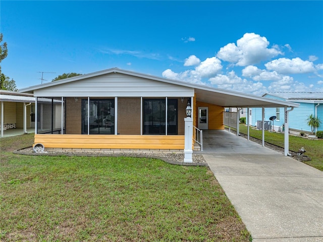 view of front of home with driveway, an attached carport, a front lawn, and a sunroom