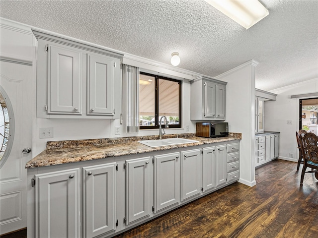 kitchen with arched walkways, gray cabinetry, a sink, ornamental molding, and dark wood-style floors