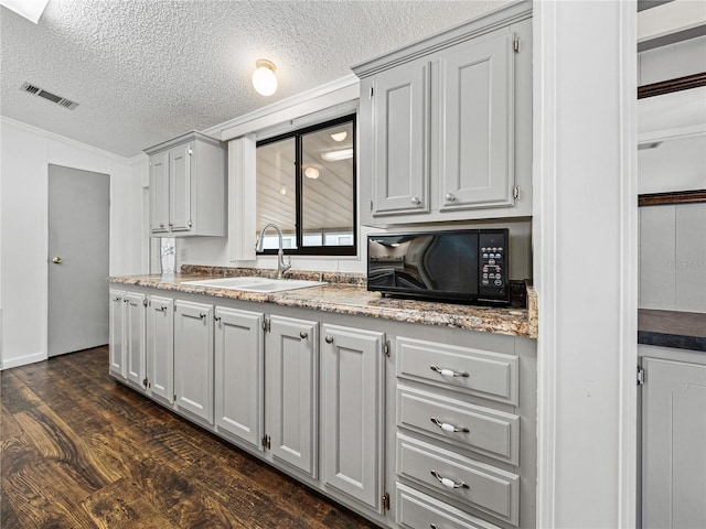 kitchen with dark wood-style floors, visible vents, a sink, a textured ceiling, and black microwave