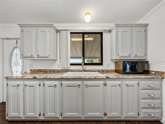 kitchen with black microwave, a textured ceiling, a sink, and crown molding