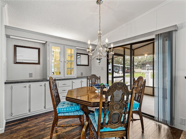 dining space featuring dark wood-style floors, a textured ceiling, an inviting chandelier, and crown molding