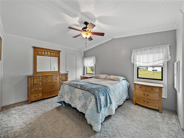 carpeted bedroom with ornamental molding, vaulted ceiling, a textured ceiling, and ceiling fan