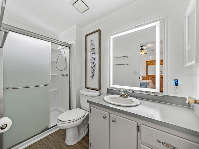 ensuite bathroom with toilet, ornamental molding, a stall shower, vanity, and wood finished floors