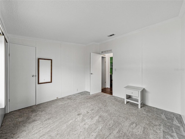 interior space with ornamental molding, carpet, visible vents, and a textured ceiling