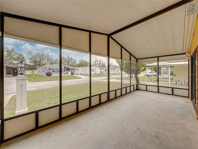 unfurnished sunroom with a wealth of natural light, lofted ceiling, and a residential view