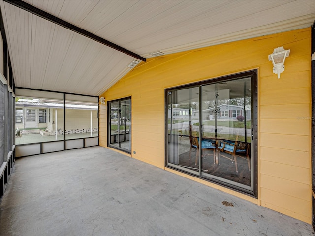 unfurnished sunroom featuring lofted ceiling with beams