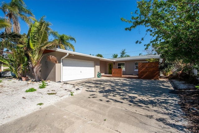 single story home featuring a garage, concrete driveway, and stucco siding