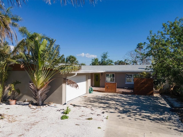 ranch-style house featuring a garage, driveway, and stucco siding