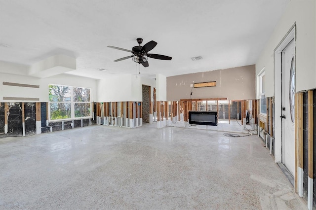 unfurnished living room with speckled floor, visible vents, and a ceiling fan