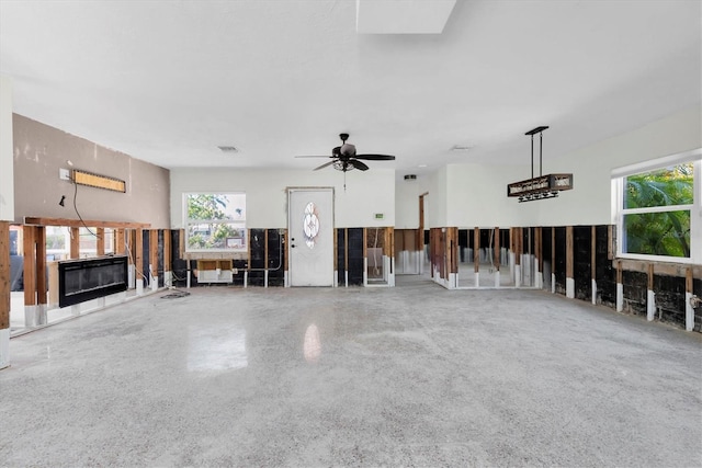 unfurnished living room with a glass covered fireplace and a ceiling fan