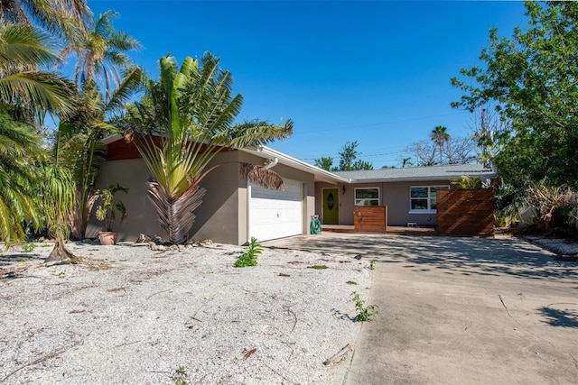 ranch-style home featuring driveway, an attached garage, and stucco siding