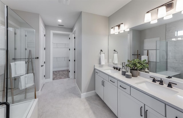 bathroom featuring a stall shower, a walk in closet, visible vents, and a sink