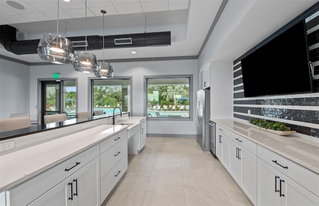 kitchen featuring visible vents, white cabinets, light stone counters, decorative light fixtures, and backsplash