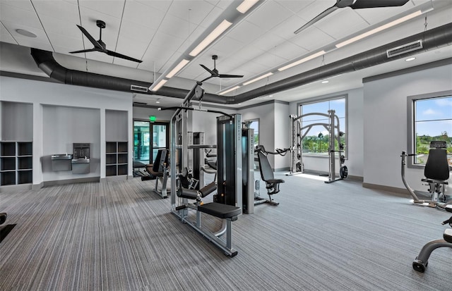 exercise room featuring ceiling fan, carpet floors, visible vents, and baseboards