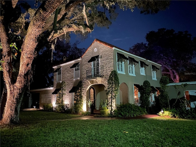 view of front of house featuring a front yard, a water view, a balcony, and stucco siding