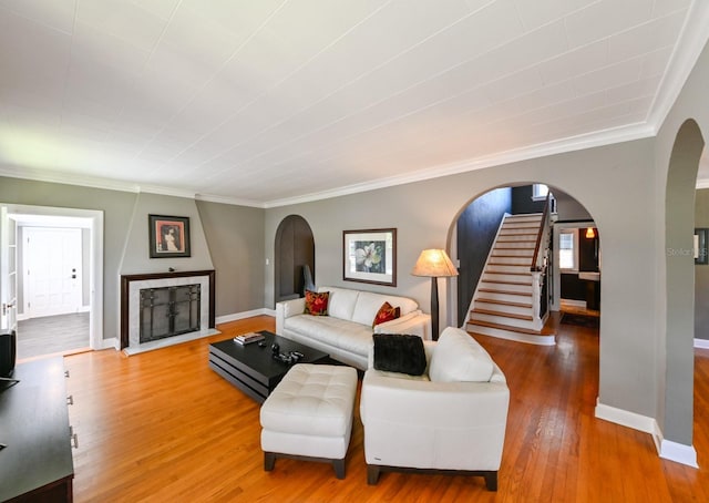 living room with arched walkways, hardwood / wood-style floors, stairway, and baseboards