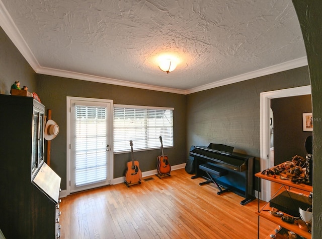 interior space with a textured ceiling, ornamental molding, hardwood / wood-style flooring, and baseboards