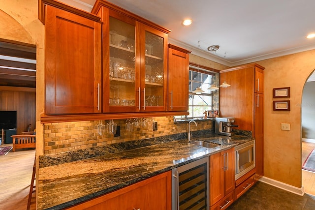 bar with tasteful backsplash, beverage cooler, arched walkways, a sink, and indoor wet bar