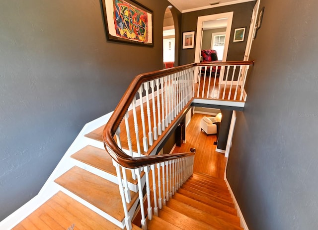 stairs featuring arched walkways, wood finished floors, visible vents, and baseboards