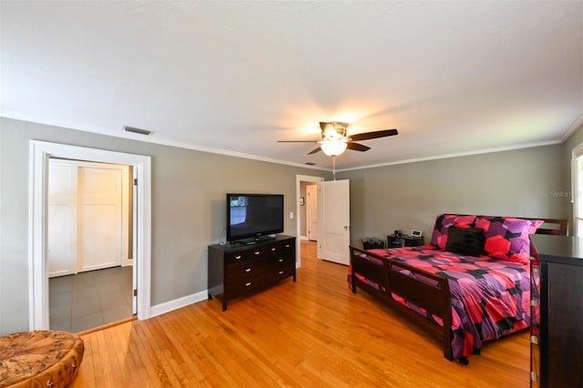 bedroom featuring ceiling fan, visible vents, baseboards, light wood-type flooring, and crown molding