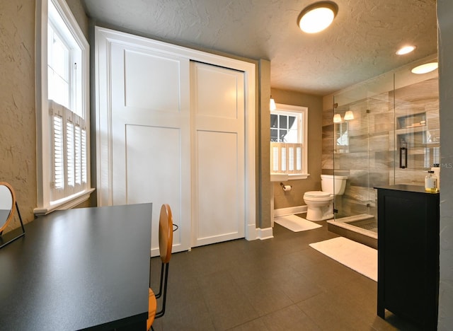 bathroom featuring a textured ceiling, toilet, baseboards, a shower stall, and tile patterned floors