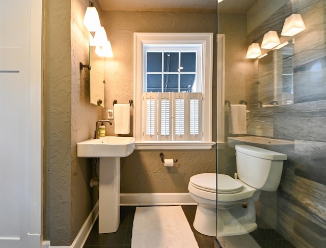 bathroom with a textured wall, toilet, and baseboards