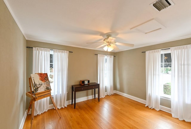 unfurnished room with crown molding, visible vents, attic access, light wood-style floors, and baseboards