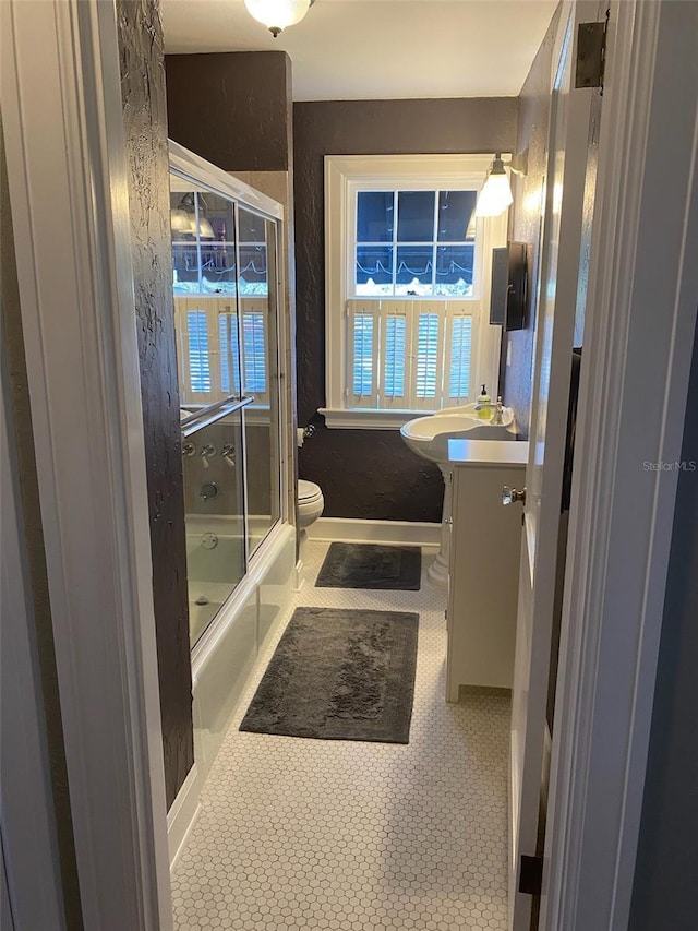 bathroom with toilet, enclosed tub / shower combo, vanity, tile patterned flooring, and baseboards