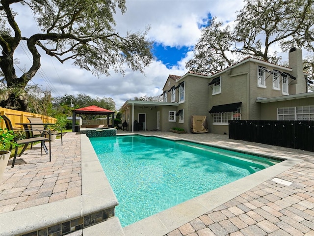 view of pool featuring a pool with connected hot tub, a patio area, fence, and a gazebo