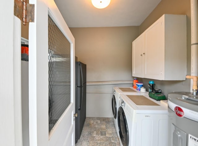 washroom featuring washer and dryer, stone finish floor, electric water heater, and cabinet space