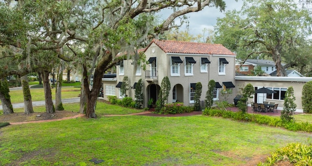 mediterranean / spanish-style home with stucco siding, a front lawn, a patio, and a tiled roof