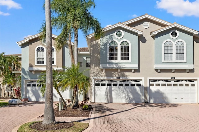 mediterranean / spanish-style house with a garage, decorative driveway, and stucco siding