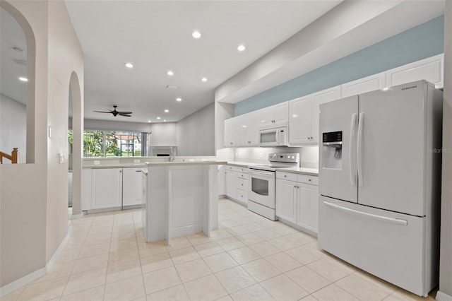 kitchen featuring white appliances, light countertops, a peninsula, and white cabinetry