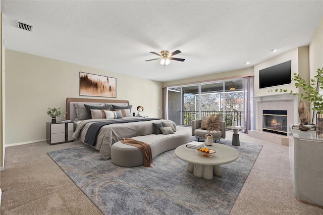 bedroom with carpet, visible vents, a textured ceiling, and a tile fireplace