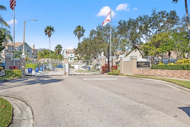 view of street with street lights, a gate, a gated entry, a residential view, and curbs