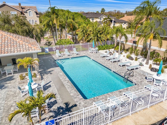 community pool with a patio and fence