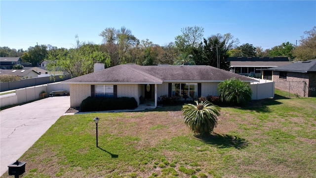 ranch-style home featuring brick siding, a front yard, and fence