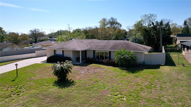 ranch-style home with concrete driveway, brick siding, fence, and a front lawn