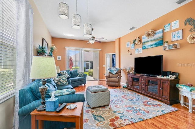 living room featuring ceiling fan, wood finished floors, visible vents, and baseboards