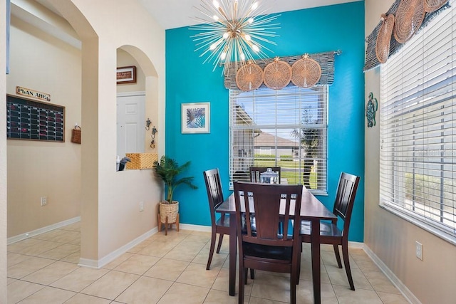 dining area featuring tile patterned flooring, plenty of natural light, arched walkways, and an inviting chandelier