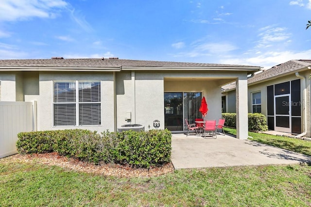 rear view of house with a yard, a patio, and stucco siding